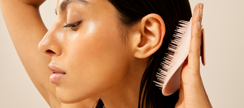 Femme se brossant les cheveux avec une brosse en silicone.