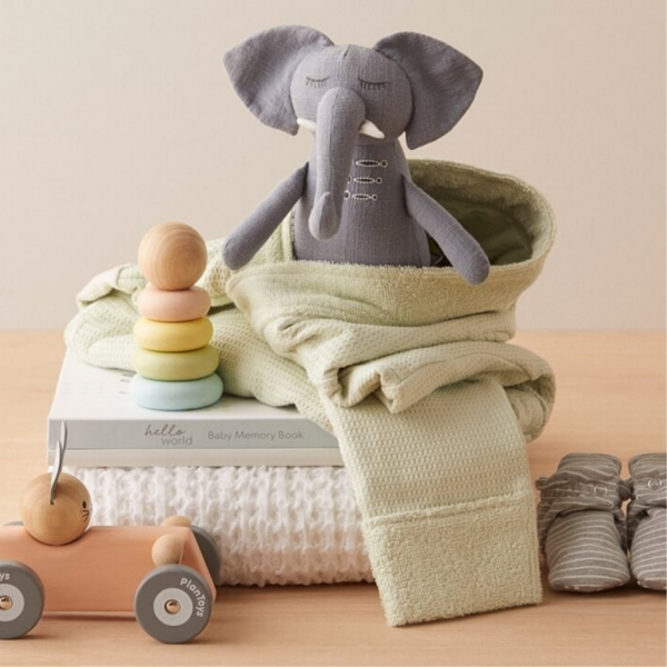 A plush elephant toy wrapped in a baby blanket.