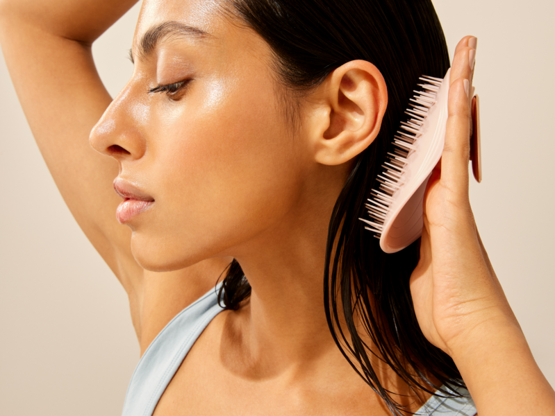 Woman brushing her hair with a silicone brush.