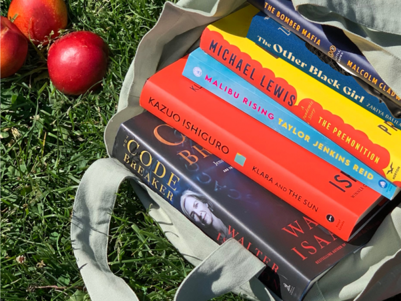 Books in tote bag on grass.