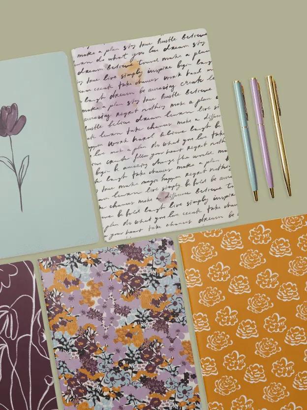 A selection of colourful floral notebooks and pens.