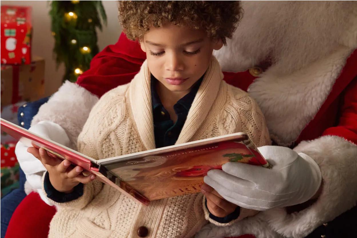 Un enfant lisant un livre de Noël avec père Noël.